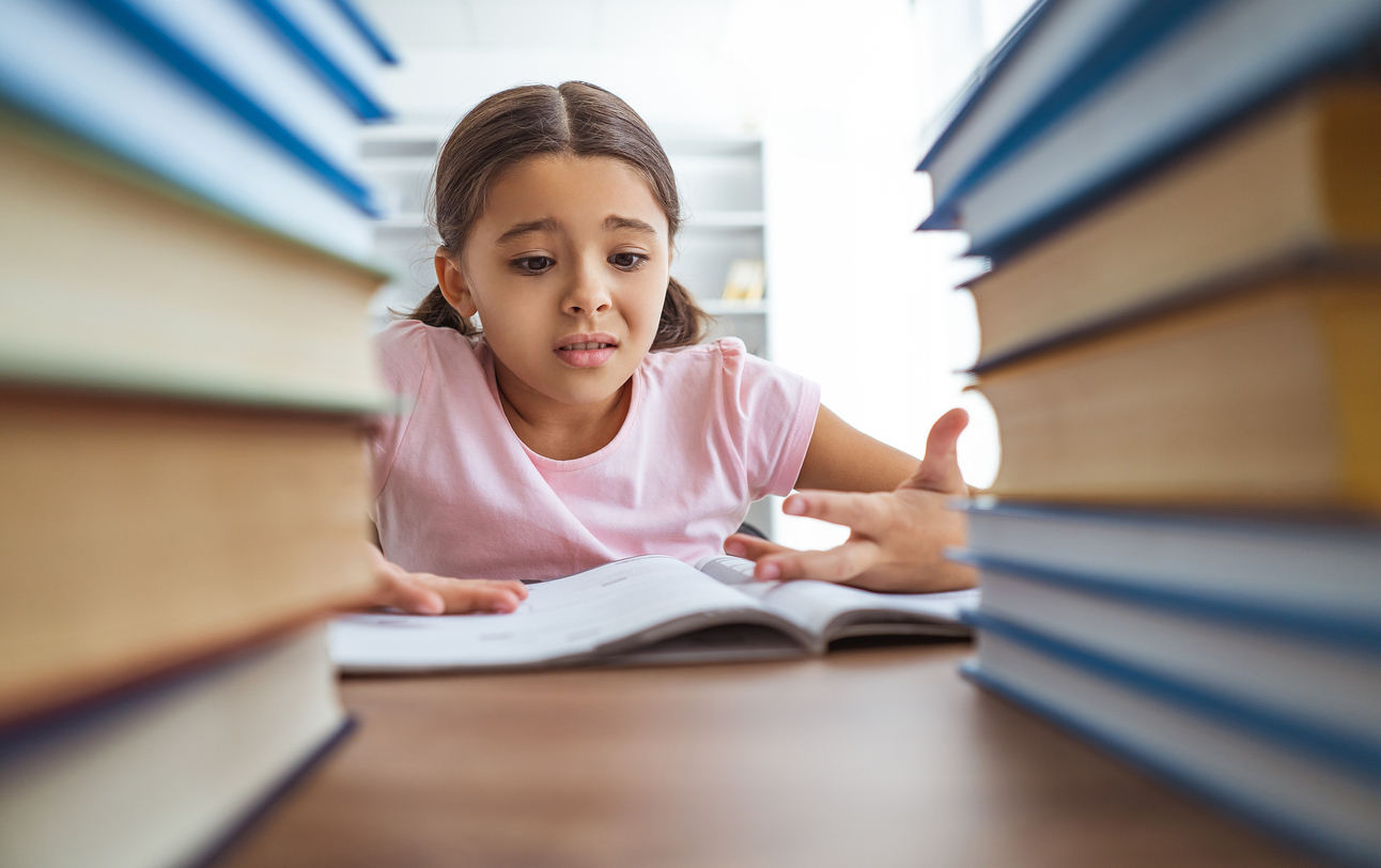 Young student in school library having trouble reading due to vision problem