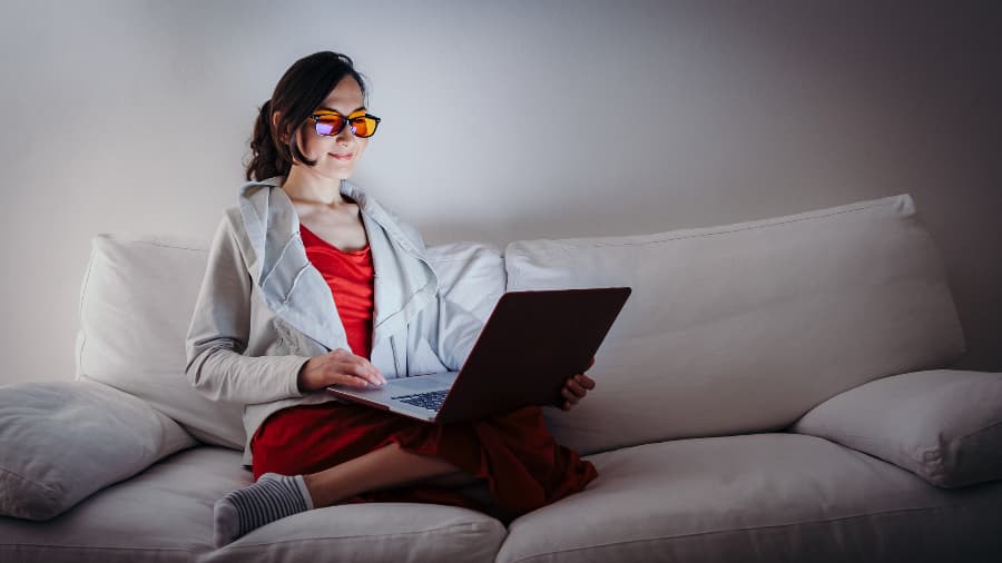 Woman wearing blue light glasses while using laptop
