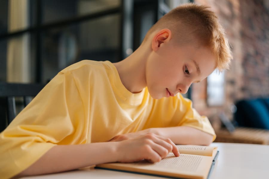 Young boy using finger as a guide while reading book