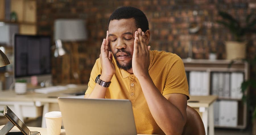 Person massaging eyes while using laptop